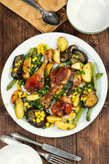 Roast chicken thigh garnished with vegetables.