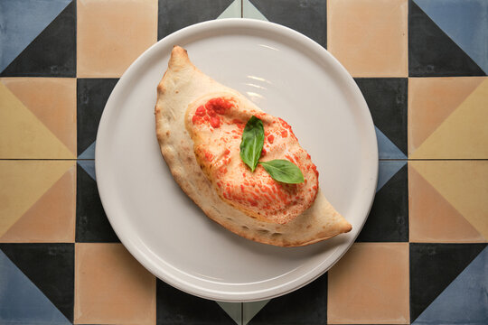 Delicious calzone with tomato sauce and basil leaves