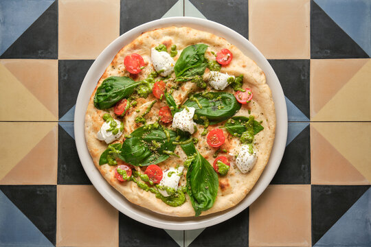 Delicious pizza with pesto, cherry tomatoes, basil and stracciatella