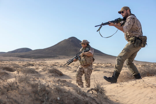 Military soldiers patrol desert landscape with rifles