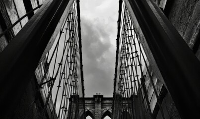 view of suspension Brooklyn bridge with cables and gates on cloudy day