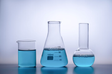 Laboratory glassware with blue liquid on reflective surface
