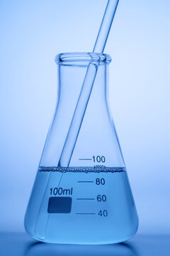 Laboratory flask and pipette with blue liquid on gradient