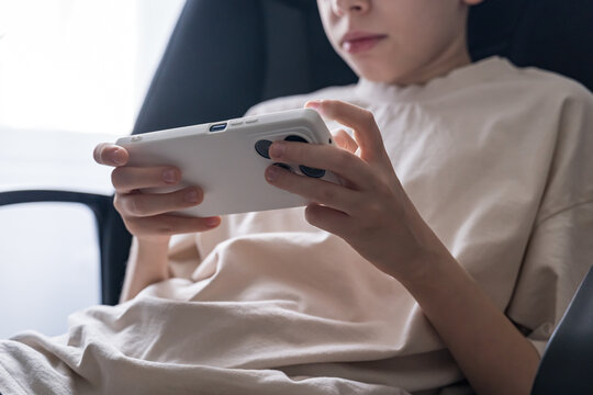 Teenage boy engrossed in mobile gaming on a smartphone