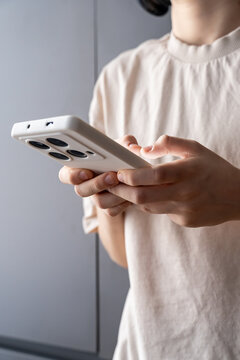 Teen Holding Smartphone with White Case Indoors, Typing or Gaming