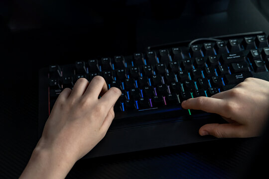 Hands Typing on Illuminated Keyboard in Gaming Setup
