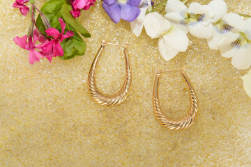 Gold Hoop Earrings with Colorful Flowers on Yellow Textured Surface

