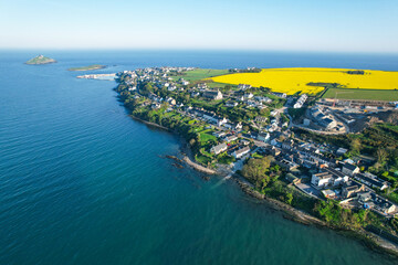 Aerial view of Ballycotton, a coastal village in County Cork, Ireland, with the ocean, lighthouse island, and yellow fields on a clear day.
