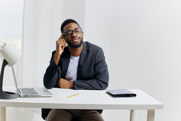 Business professional working on laptop and phone at office desk, focused on task management and...