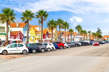 Colorful striped houses called Palheiros with car and palm tree. Costa Nova do Prado is a beach village resort on Atlantic coast near Aveiro, Portugal