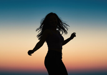Silhouette of young asian female dancing at sunset