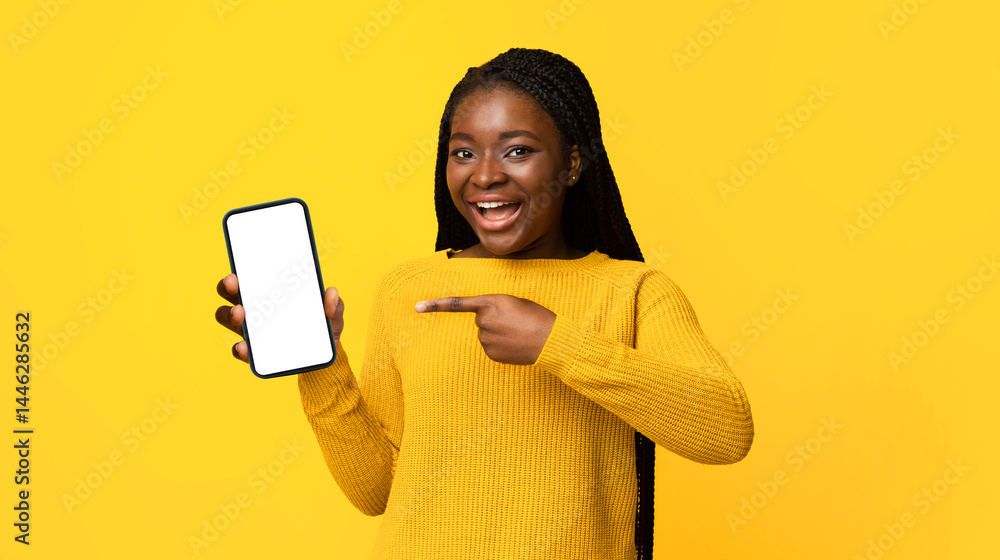 Poster smiling african american female pointing on blank black smartphone screen, demonstrating free place 