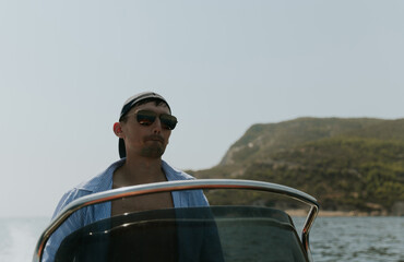 A young guy controls a boat on the sea.