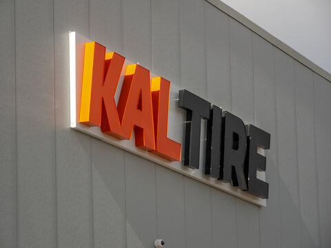 Calgary, Alberta, Canada. Apr 30, 2025. The illuminated "KAL TIRE" sign, with orange "KAL" and black "TIRE" lettering, mounted on a vertically paneled wall.