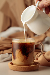 Pouring cream in black coffee.