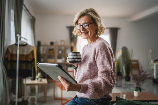 mature blonde woman with eyeglasses use digital tablet at home