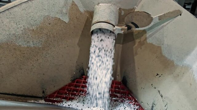 Plastic Granules Flowing from Industrial Pipe into Processing Unit

