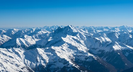 Obraz premium Aerial view of snow capped mountain range under a clear blue sky on a bright sunny day landscape
