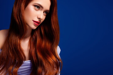 Portrait of a young woman with long red hair in a glamourous style on a vibrant blue background