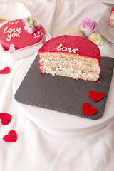 Red valentine's cake slice with heart decorations on slate plate