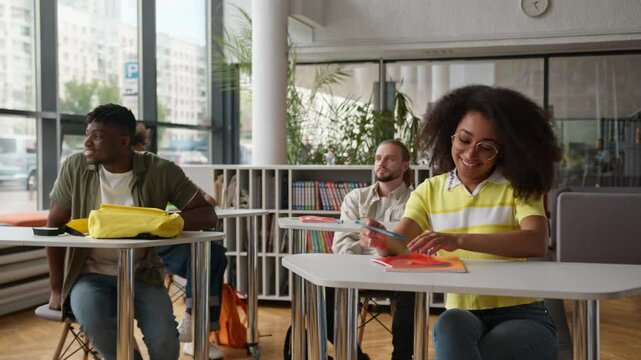 African American man guy male student coming in classroom sitting table smiling with multiethnic diversity students classmates in class start education studying day in high school university college