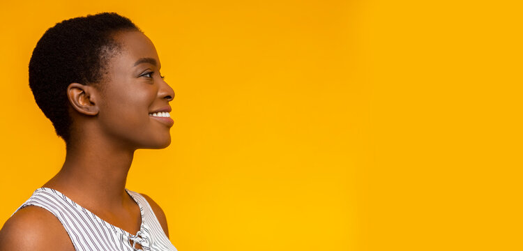 Happy smiling african american girl profile portrait. Black woman looking aside at copy space