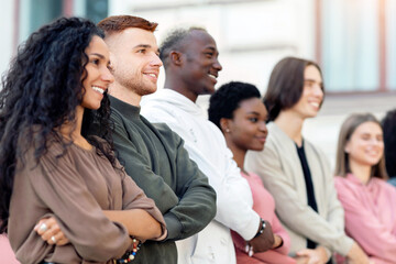 International group of cheerful students holding hands and chanting slogans while walking by street towards government building, multiracial activists having strike, feeling excited and invincible