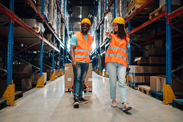 Fototapeta premium Warehouse workers managing inventory and logistics using handheld devices and pallet jack