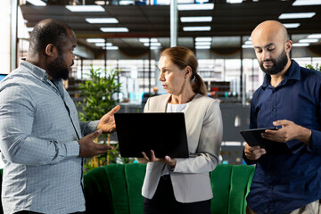 Multiracial workers using laptop device to write emails, solving tasks. Staff members typing on...