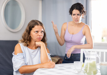 Young bored woman ignoring her female partner yelling aggressively with wrathful expression, LGBTQ family problems