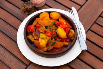 Ojahuri or fried meat with potatoes, parsley and tomatoes in clay pan. Georgian cuisine