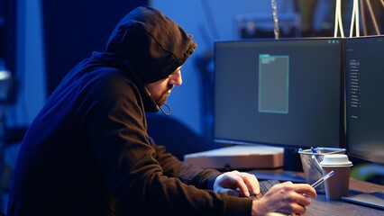 Hacker in abandoned warehouse talking on phone with partner, stealing data after using phishing...