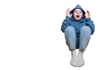 Surprised or scared child sitting in blue hoodie with hands raised, mouth open. Isolated on a...