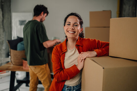Happy couple moving into new home arranging cardboard boxes