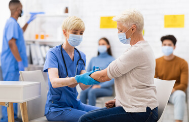Obraz premium Covid-19 Vaccination. Senior Patient Lady Getting Vaccinated Against Coronavirus Sitting With Doctor In Hospital, Wearing Face Mask. Nurse Injecting Corona Virus Vaccine Shot To Older Woman