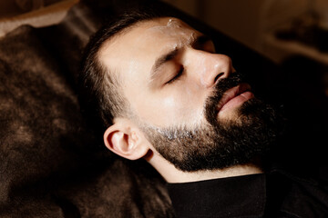bearded man in the spa for beauty and mud and hydrating mask. Wellness, therapy and health with a...