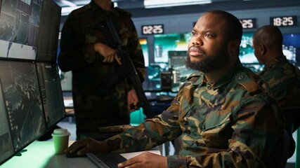 Fototapeta premium Counterintelligence specialist in military HQ base gathering information on enemy troops. African american agent in base of operations doing assessment of enemy vulnerabilities, tracking, camera B