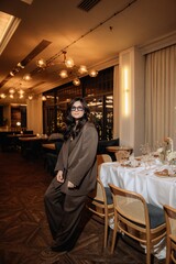 photo of a stylish brunette in glasses against the background of a restaurant interior with blurred...