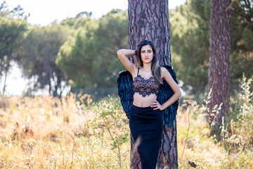 Woman in the forest posing with dark wings