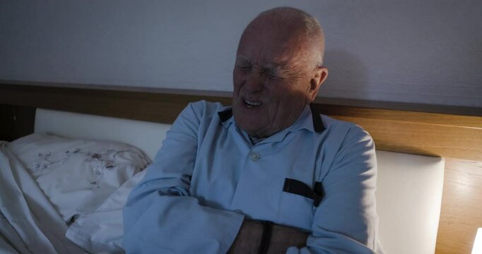 Sick, stomach pain and senior man in bed with a problem in the liver or pancreas at night. Insomnia, sad and frustrated elderly man with medical pain, emergency and body fail in the dark bedroom