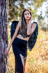 Woman in the forest posing with dark wings