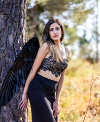 Woman in the forest posing with dark wings