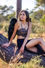 Woman in the forest posing with dark wings