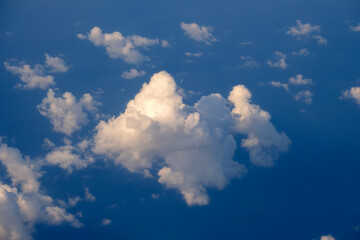 Cloudy sky, from airplane window point of view. View from above at high altitude of dense puffy...