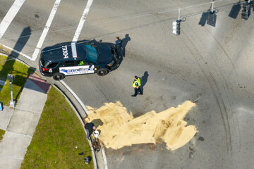 Wrecker operator workers cleaning up road surface after car crash. Sand absorbing spilled engine...