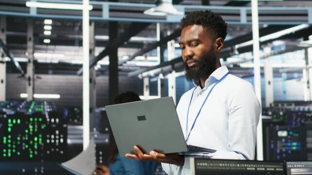 Data center programmer uses node tree software to identify equipment performance issues. African american server farm worker reviews data analysis graph to minimize hardware failures, camera B