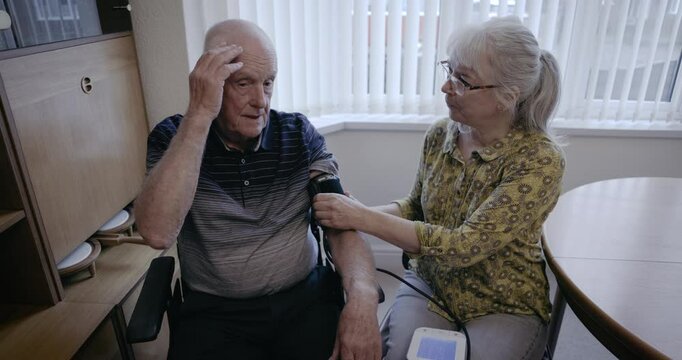 Blood pressure, old couple and home check for health test, cholesterol and cardiology. Senior man worried about hypertension, diabetes risk and medicare from arm pulse, wellness and medical support