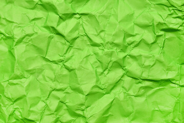 A textured green crumpled paper background with natural creases and folds. Ideal for design projects, digital graphics, or creative presentations requiring a vibrant, tactile surface element