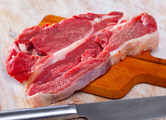 Raw juicy boned steak cut off beef sirloin ready for cooking on wooden table