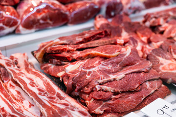 Raw beef meat laid out on counter in butcher shop..